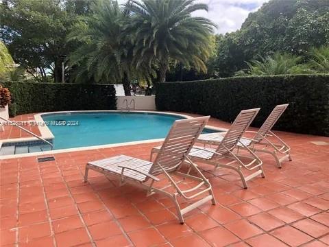 Outdoor swimming pool area with lounge chairs and surrounding greenery.