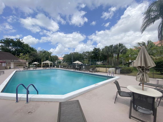 Outdoor swimming pool with patio chairs and umbrellas.