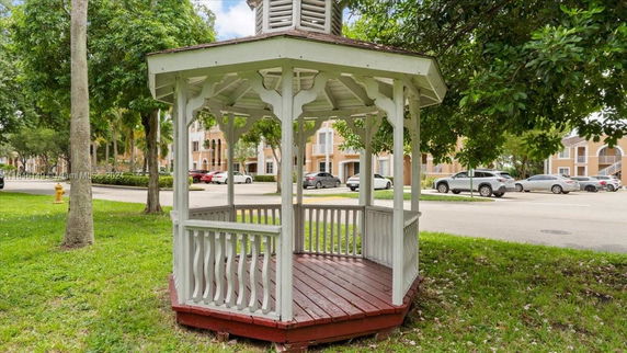 Gazebo near residential buildings with parked cars on the street.
