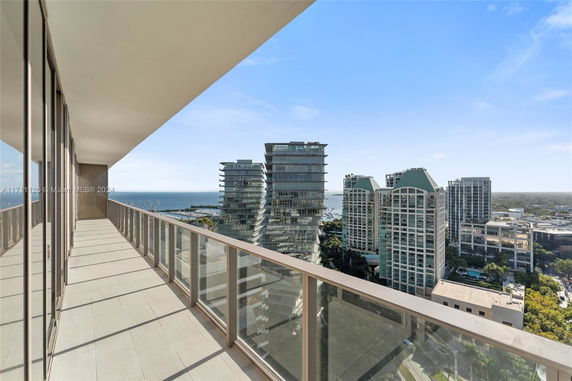Panoramic view from a high-rise balcony overlooking city buildings and ocean.