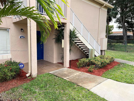 Front view of a building entrance with outdoor stairs and a blue door.