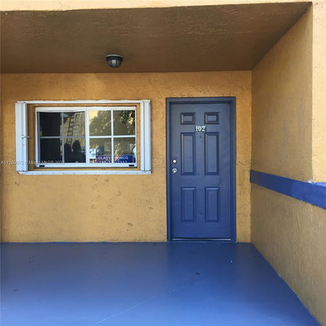 Front view of a building entrance with a blue door and window.
