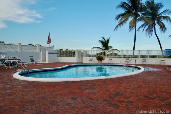 Outdoor swimming pool area with surrounding patio and palm trees.