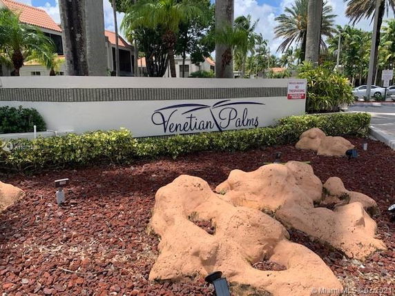 Front view of a sign for Venetian Palms with surrounding landscaping.