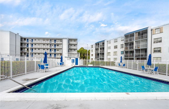 Outdoor swimming pool area with surrounding apartment buildings.