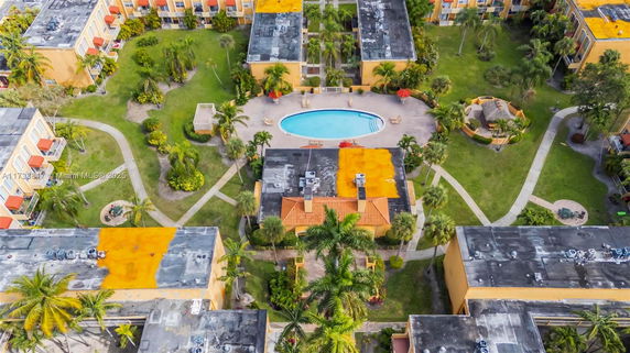 Aerial view of a residential complex with several buildings surrounding a central swimming pool.