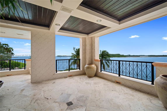 Covered balcony with elegant railings overlooking a body of water and distant land.
