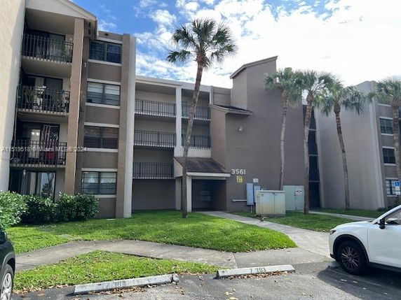 Front view of a multi-story apartment building with balconies and palm trees.