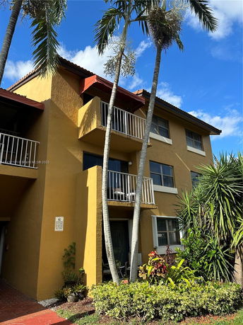 Front view of a multi-story building with balconies and a yellow exterior.