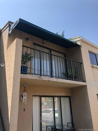 Front view of a two-story building with balcony and awning.