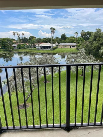 View of a residential area with houses and a pond, seen from a balcony.