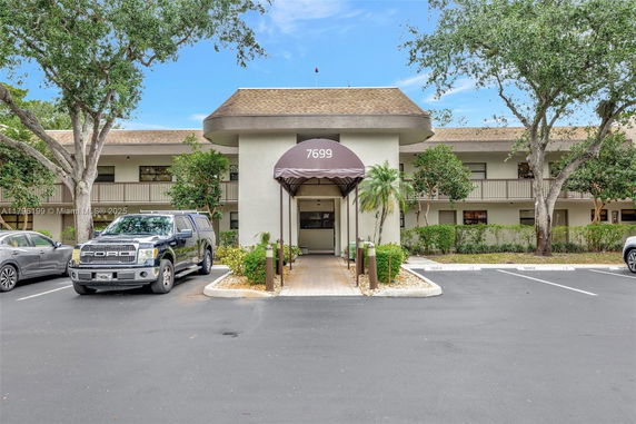 Front view of a two-story building with an entrance canopy and parking area.