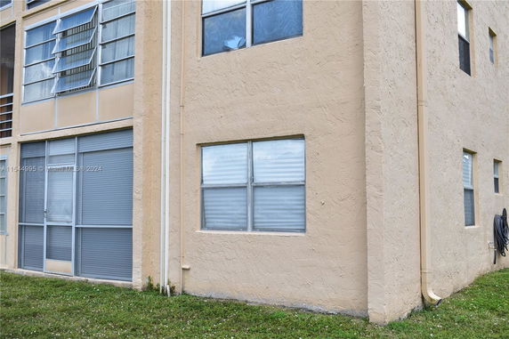 Corner view of a beige multi-story building with windows and applied stucco finish.