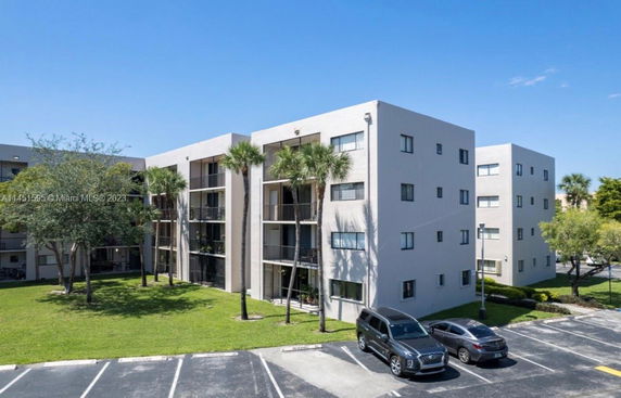 Front view of a multi-story residential building with balconies and parking area.