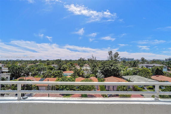 Panoramic view of surrounding residential area with houses and trees under a blue sky.