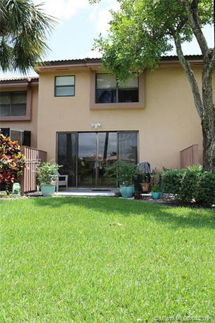 Front view of a two-story house with a patio and sliding glass doors.