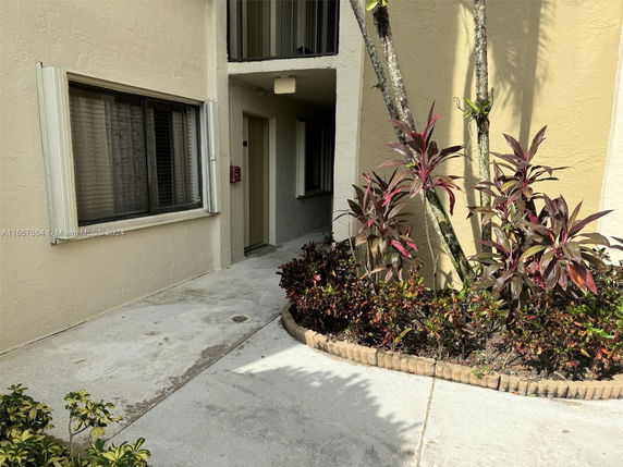 Front view of a building entrance with plants along the pathway.