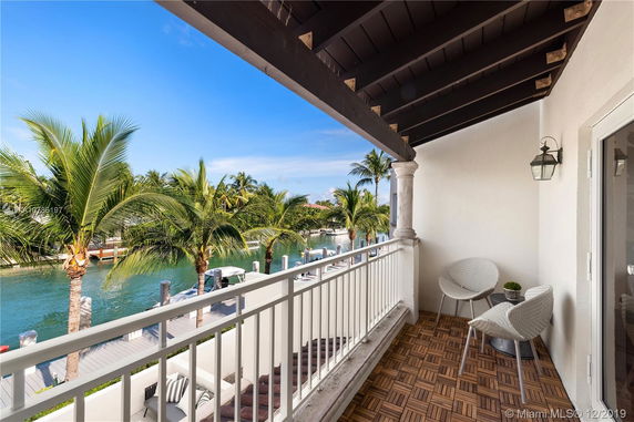 Balcony view overlooking a canal lined with palm trees and a wooden deck.