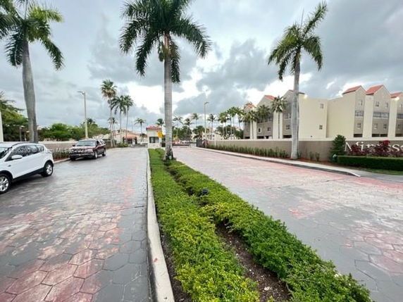View of an outdoor area with palm trees and buildings in the background.