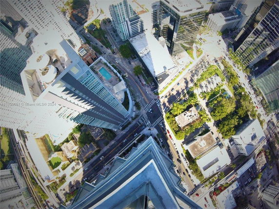 Aerial view looking down on a cityscape with high-rise buildings, streets, and surrounding greenery.