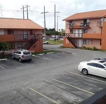 Outdoor parking area in front of two-story apartment buildings.