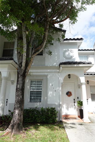 Front view of a two-story house with white exterior and decorative columns.