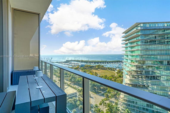 Balcony view overlooking high-rise buildings and a coastal area.