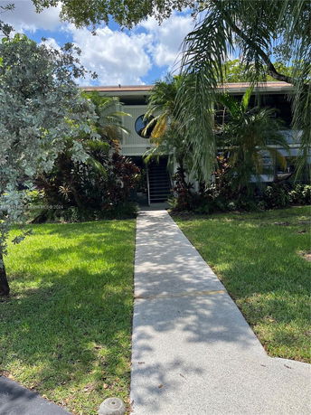 Front view of a two-story house with a circular window and a pathway leading to it.