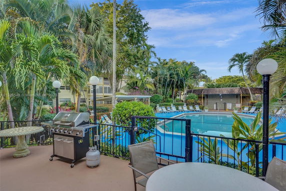 Outdoor swimming pool area with surrounding greenery and patio furniture.