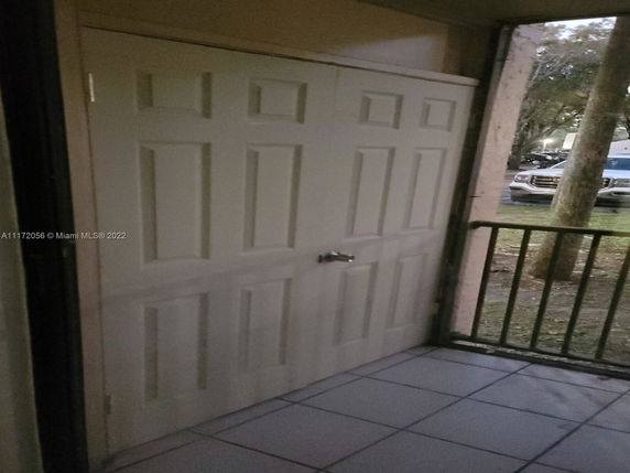View from a doorway showing a parking area with cars and trees.