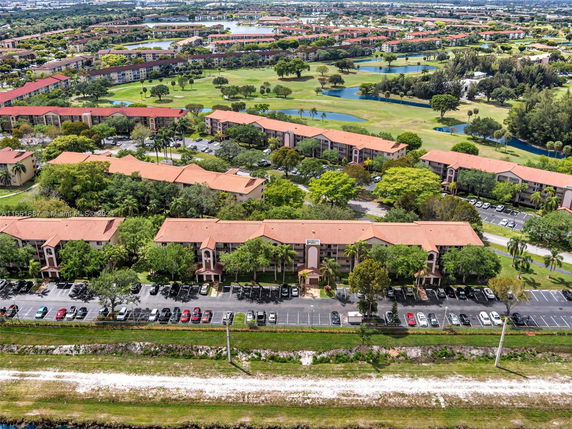 Wide-angle view of residential buildings with red roofs surrounded by green lawns and parking areas.