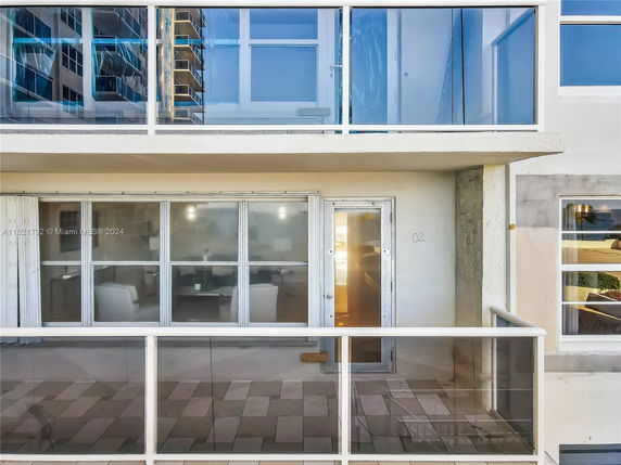 Front view of a building with glass railings and sliding glass doors leading to a balcony.