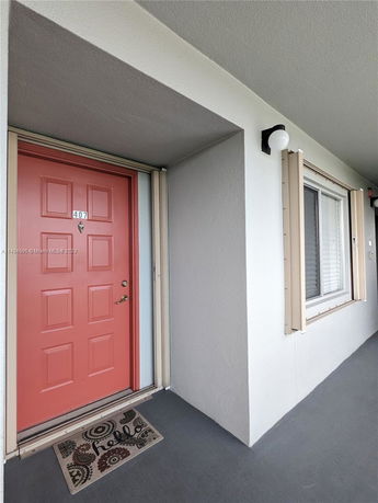 Front view of a building entrance with a pink door and a nearby window.