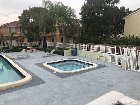 Outdoor swimming pool area with a hot tub and lounge chairs.