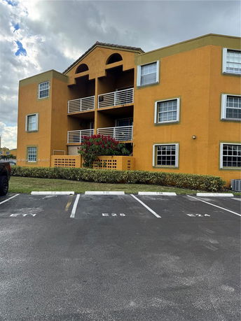 Front view of a three-story building with multiple balconies and a distinct yellow-orange facade.
