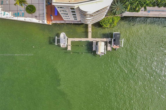 Aerial view of a waterfront building with boats docked at a pier.