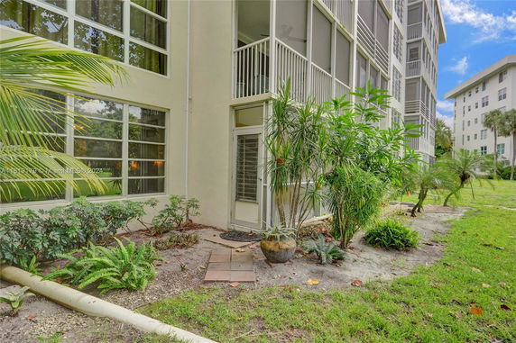 Exterior view of a multi-story building with screened balconies and surrounding landscaped area.