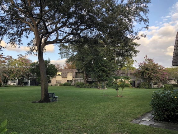 View of a residential building with a spacious grassy area and trees in the foreground.