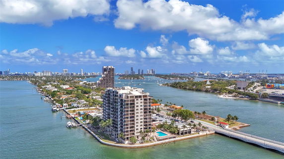 Panoramic view of waterfront buildings and city skyline across a bay.