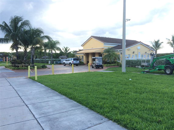Front view of a single-story building with a driveway and palm trees.