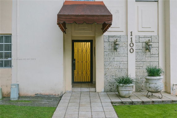 Front view of a building entrance with a decorative iron door and an overhanging awning.