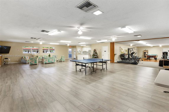 Large indoor recreation space with a table tennis setup, exercise equipment, and seating area.