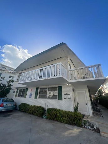 Front view of a two-story house with a balcony and a driveway.