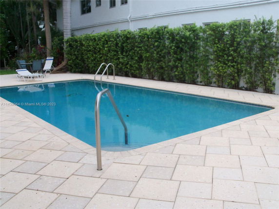 Outdoor swimming pool with surrounding patio and greenery.