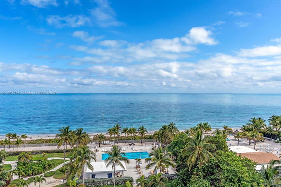 Panoramic view of a beach with palm trees and a swimming pool.