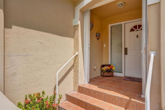 Front view of a house entrance with decorative tiles and a white door.