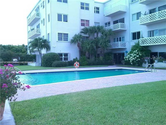 Outdoor swimming pool adjacent to a multi-story residential building.
