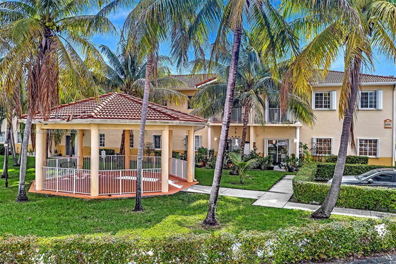 Front view of a two-story building with a gazebo and palm trees.