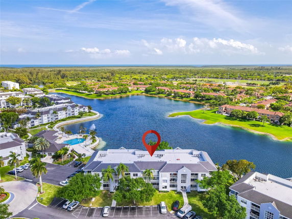 Panoramic view of residential buildings by a lake with surrounding greenery.
