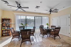 Indoor recreation area with tables and chairs, featuring ceiling fans and large windows.